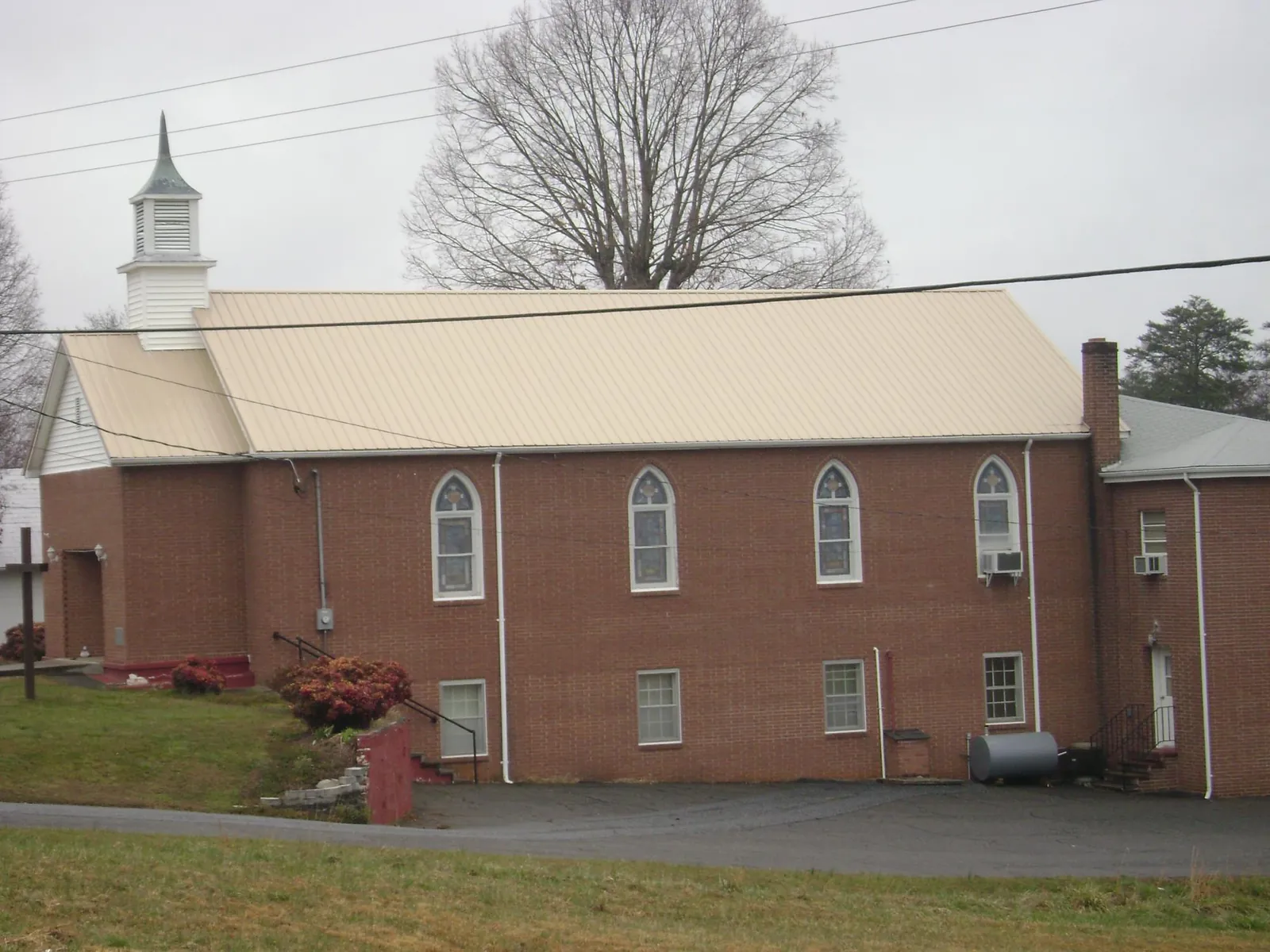 New tan metal roof on a brick church with a white steeple in Stafford